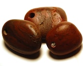 three red drilled beach stones: natural drilled beach rocks