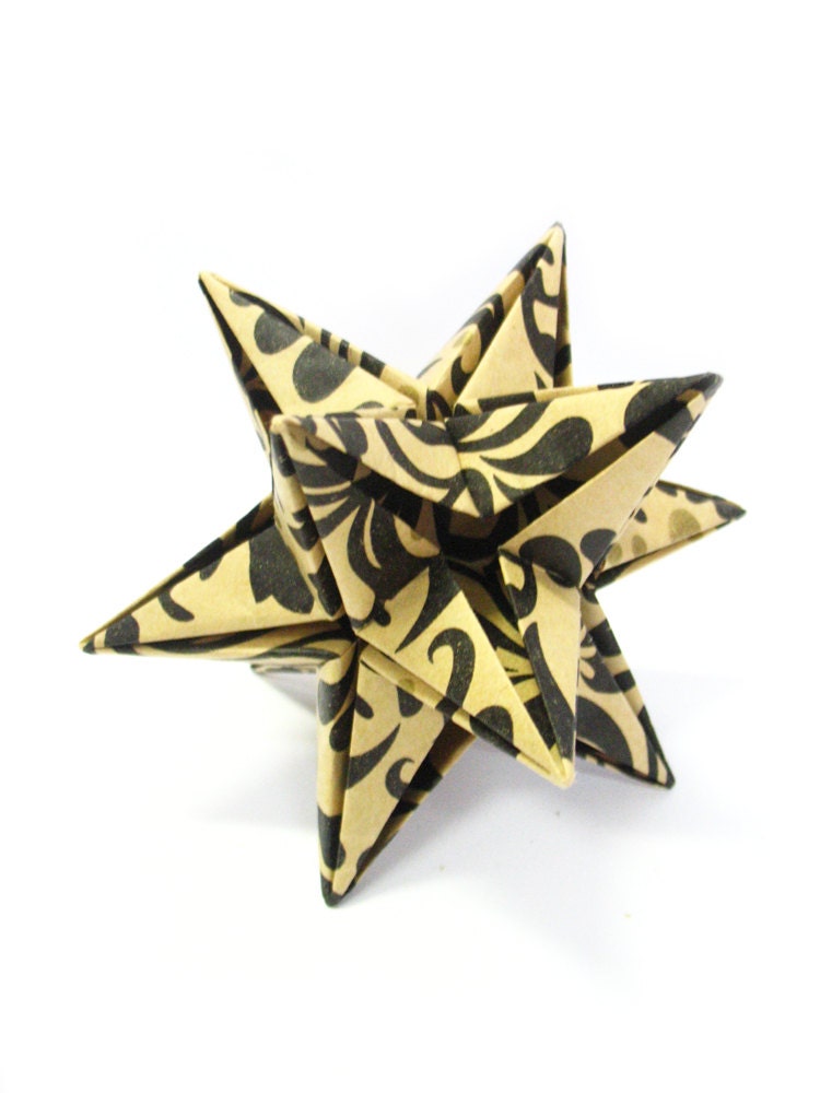Origami star, paper ornament, handmade, black leaves and gold dots against a pale brown background