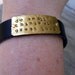 A riveted, brown leather cuff bracelet with hand stamped brass do small things with great love- distressed and embellished wording