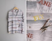 vintage men's '70s light grey 'FLY PLANE' airplane NOVELTY print short sleeve button-up shirt. size l xl.