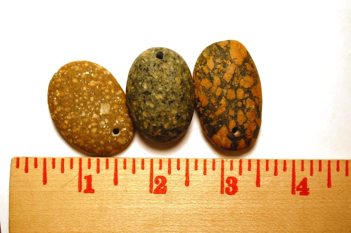 three mottled stones, drilled beach rocks with inclusions