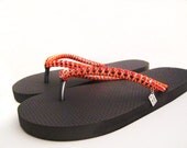 Women decorated custom made flip flops. Designed orange and black rubber sandals with gems