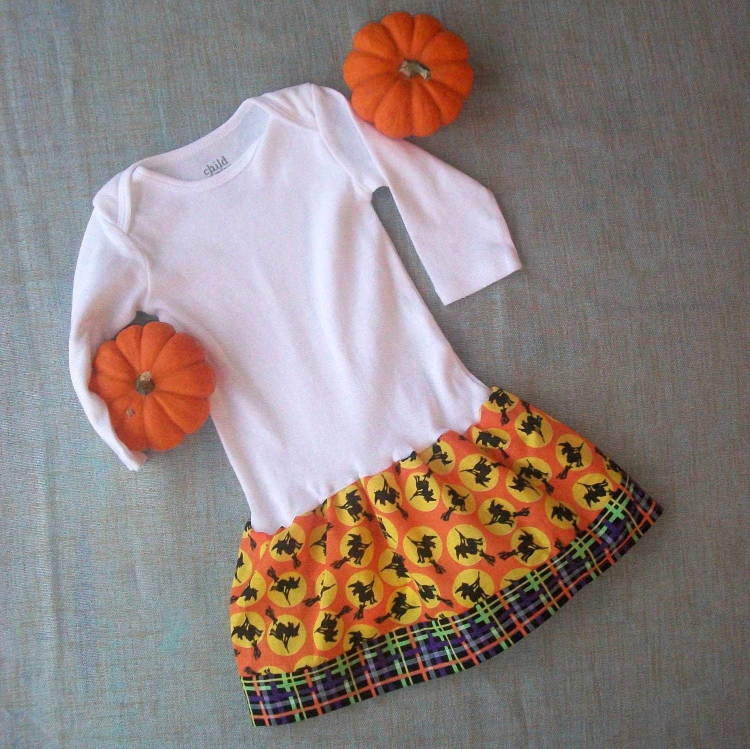 Order now in time for Halloween. Only one size 3-6 months long sleeve baby onesie with skirt. Witches on broomstick over moon, plaid stripe.