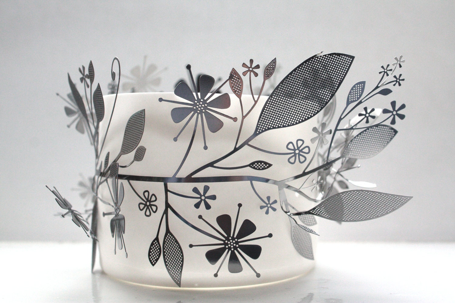 Metal foliage wrapped around a fine bone china vessel