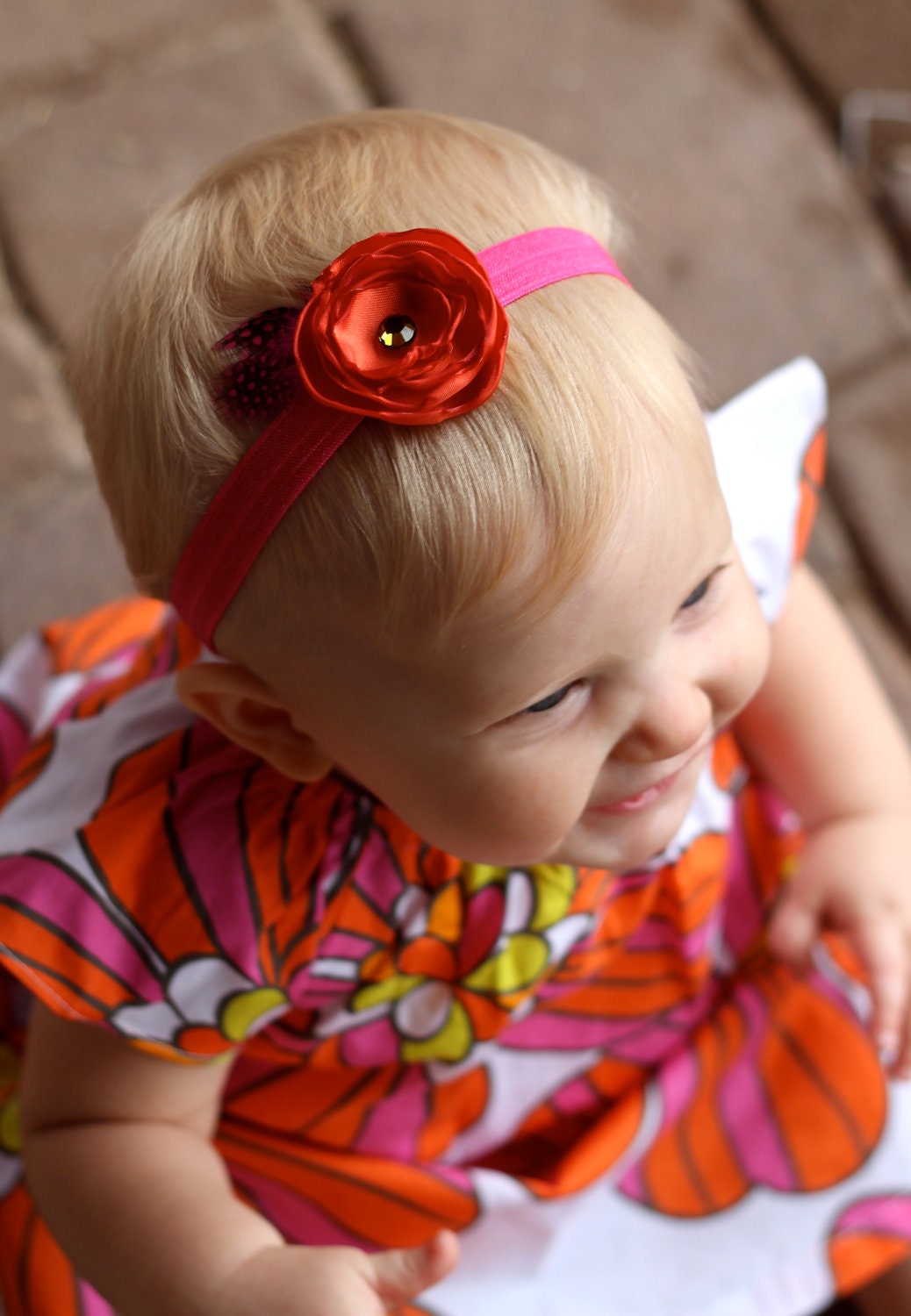 The Tangy Tangerine. Orange satin baby girl headband with bright pink feather, crystal, & elastic accents.