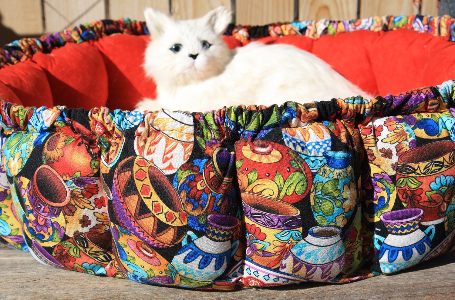 Round Cat Bed Covered In Bright Colored Pottery With A Red Inside
