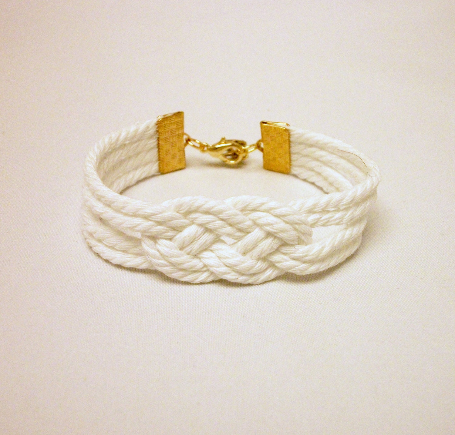 Matte white knotted nautical rope bracelet with gold anchor charm