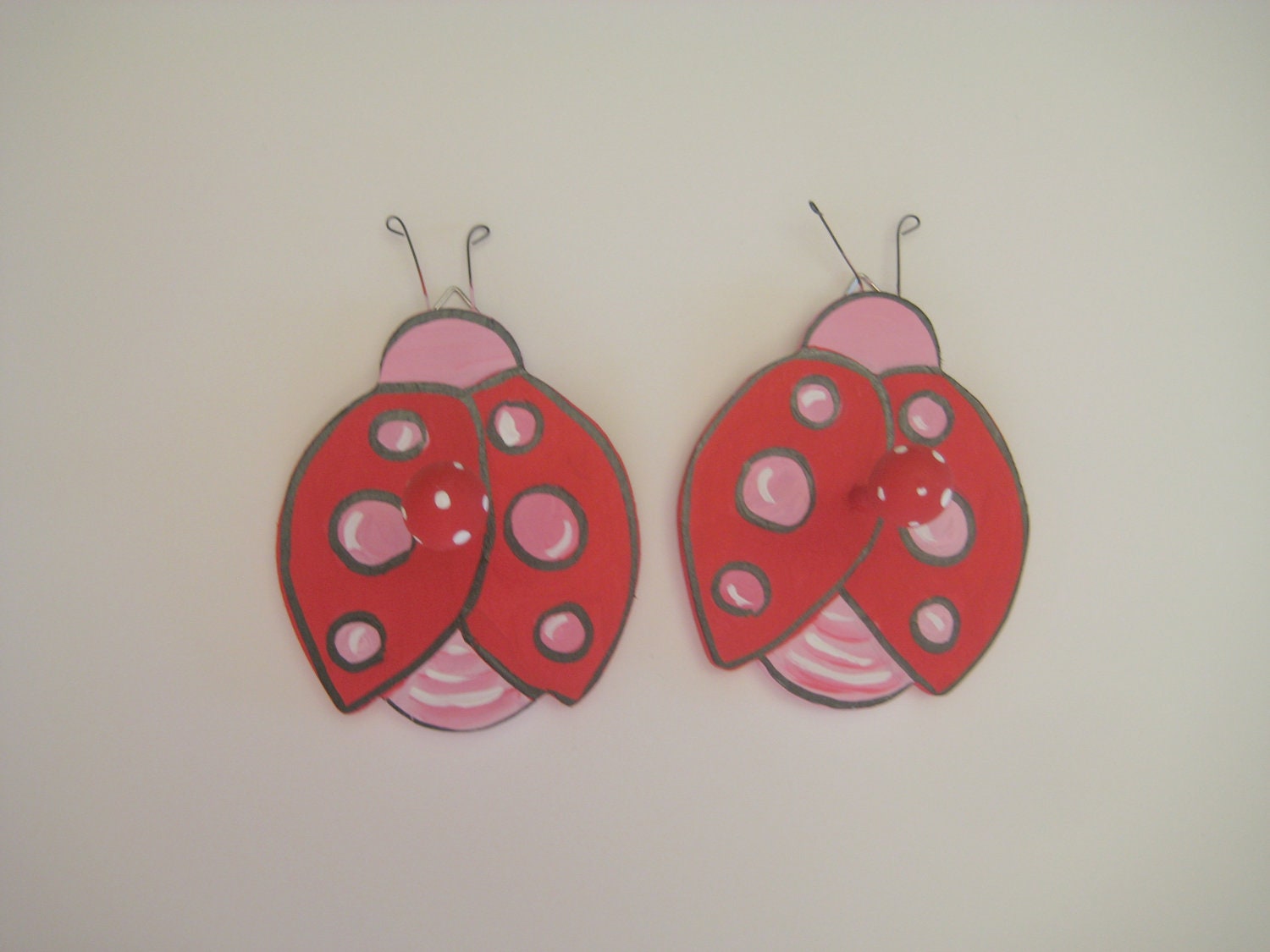 Two wooden hand painted lady bug hooks in bright red and pink