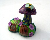 Cute miniature millefiori mushroom house with violet flowers and bee