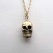 Gold skull charm necklace on delicate 14k gold plate chain, satin finish