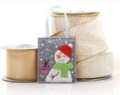 Felt Christmas ornament, snowman holding a little purple ornament, hand embroidery, red hat with pom pom, green silk scarf