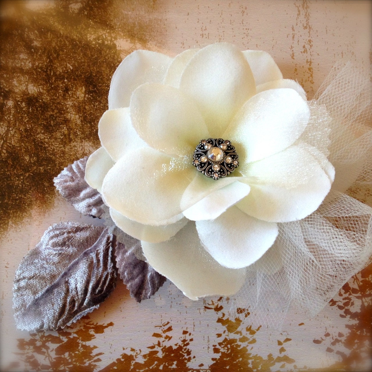 Soft off white magnolia hair clip with ivory tulle and vintage silver velvet leaves. Rhinestone antique silver center on alligator clip.