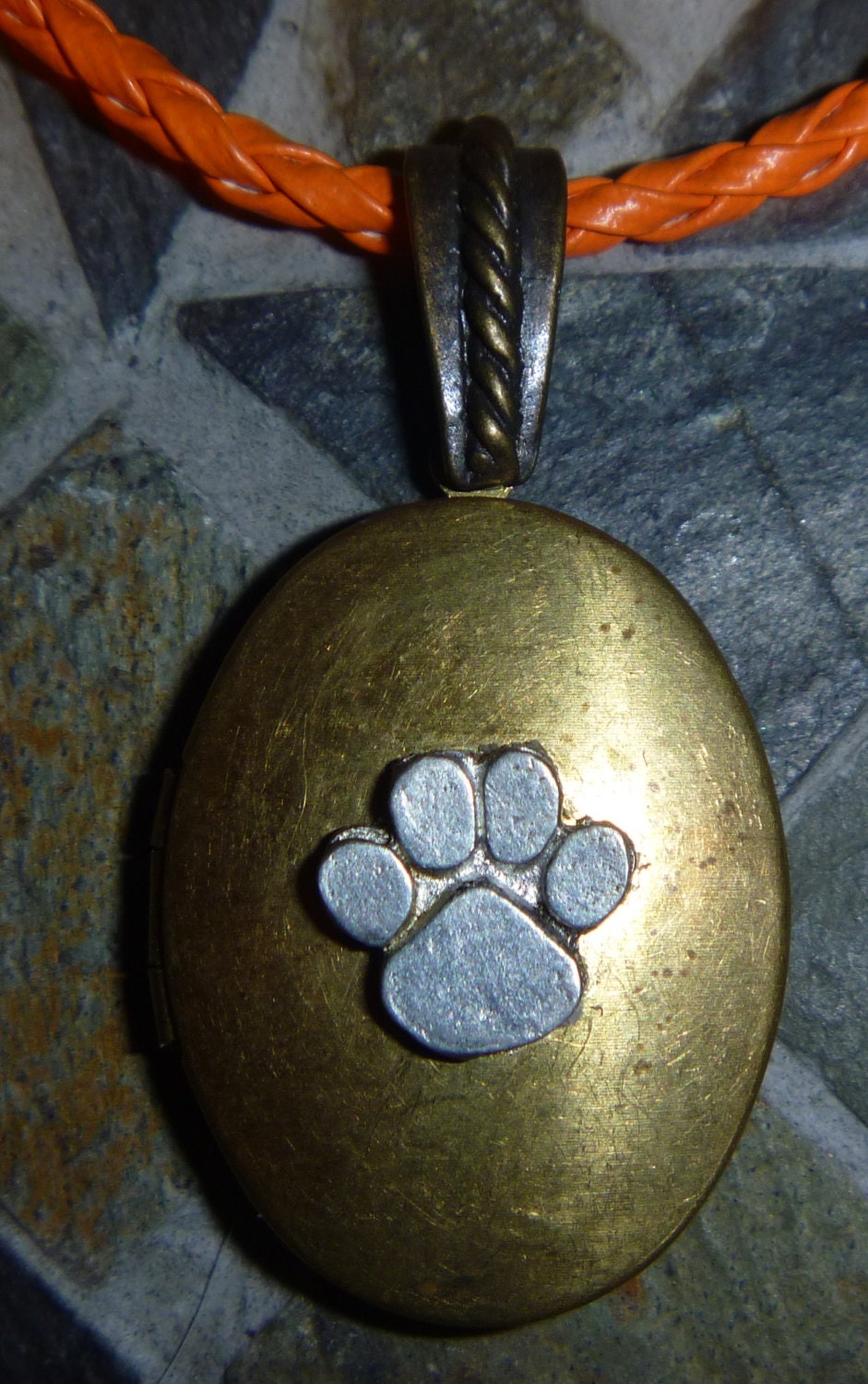 Oval antique brass locket with  paw and orange cord
