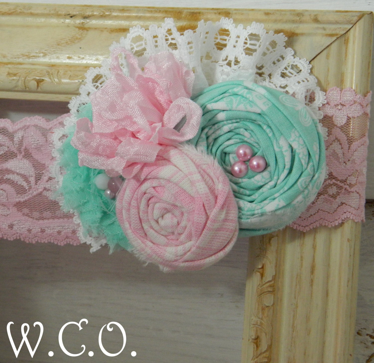 the NORAH Pink and Seafoam Rolled Fabric Rosette Headband with Eyelet Lace and Seam Binding Bow