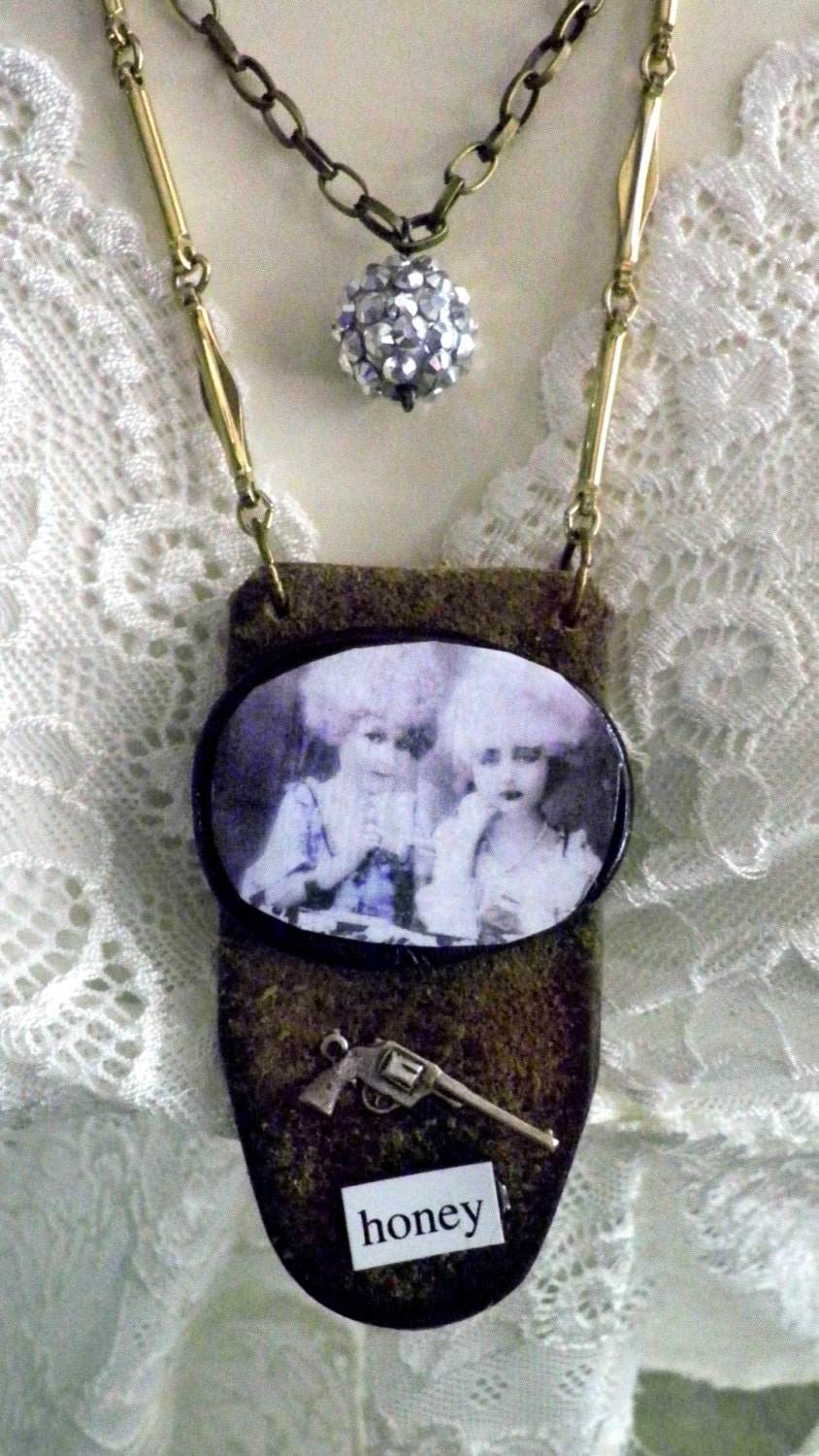 Rock and roll assemblage piece with rhinestone round dangle, leather, and handhewn clay center