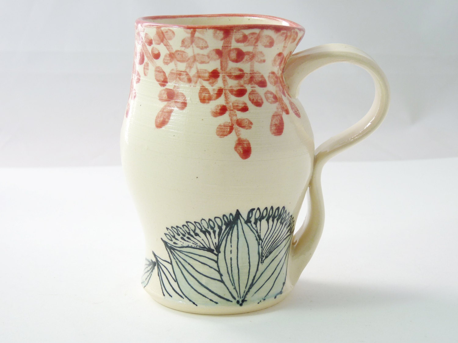 Tall mug glazed with floral design in orange and green