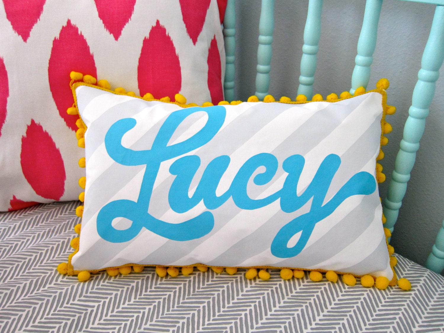 Personalized baby pillow with gray stripes and name in aqua blue.