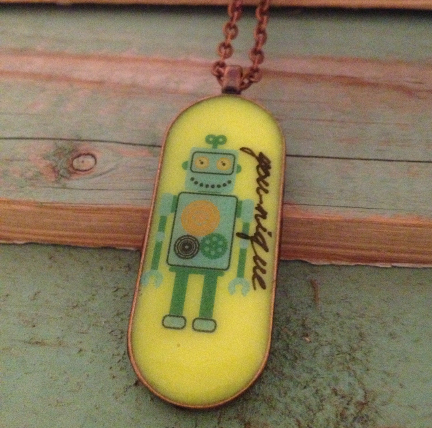 Yellow resin robot pendant with word 'you-nique'. Large oval 45mm x 18. Copper finish. Quirky