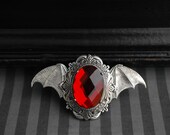 Wings of the Night - antique silver brooch with bat wings and red glass cabochon
