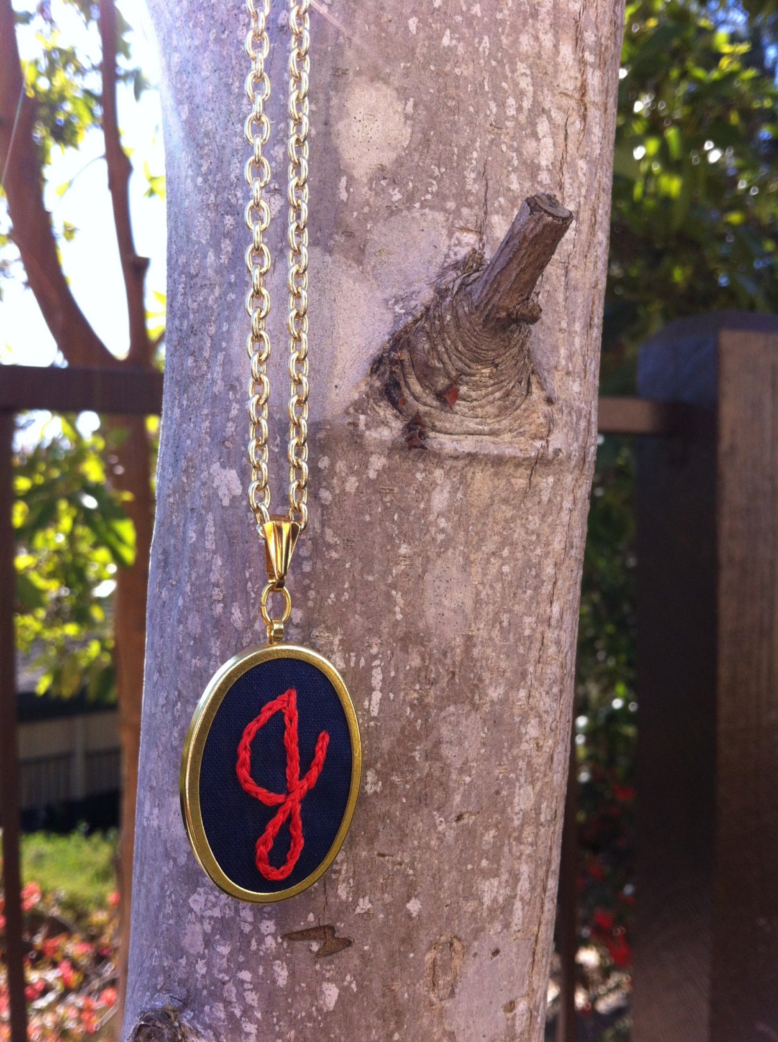 Necklace - Embroidered coral "J" on navy blue cotton, 1in x 1.5in gold oval pendant, 18 inch gold chain