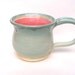 Wheel-thrown pot-bellied mug in soft blue and pink glazes with handle on white stoneware