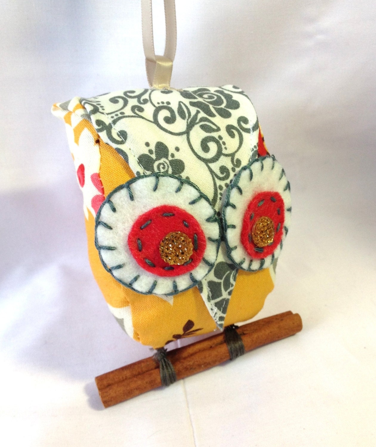 Small owl ornament in shades of orange, grey and yellow.