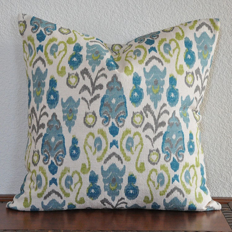 Decorative throw pillow cover in aqua, taupe and lime green on a creamy ivory background.