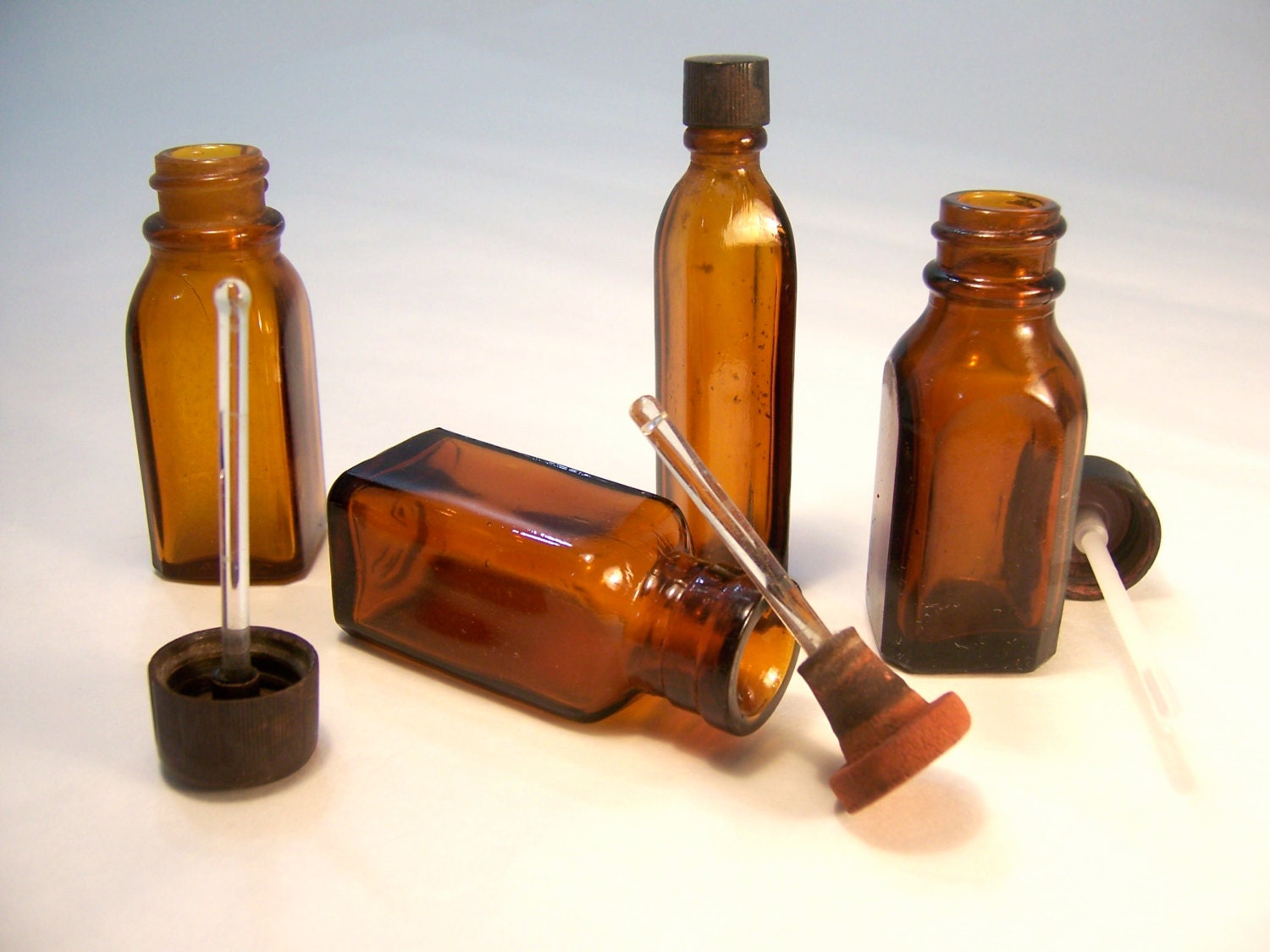 4 Brown or amber glass vintage medicine bottles with droppers and stoppers.