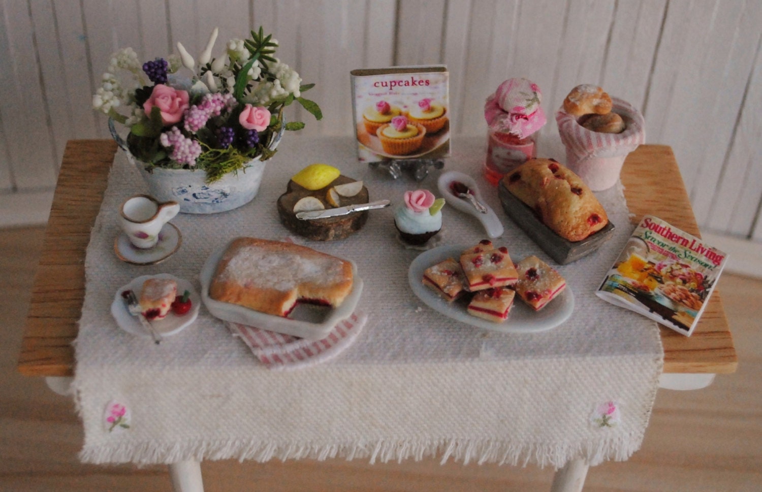 Miniature Cottage Style Baking Table Filled With Baked Goods, A Beautiful Floral Arrangement, And More