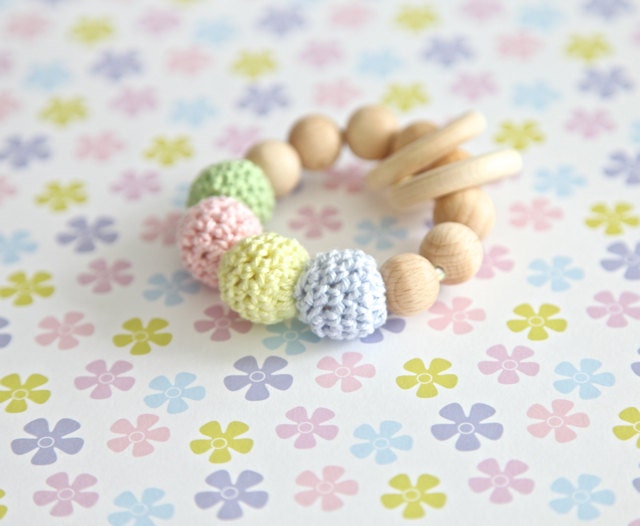 Rattle toy for baby, small teething ring in pastel colors. Wooden teether in light green, pink, blue and yellow.