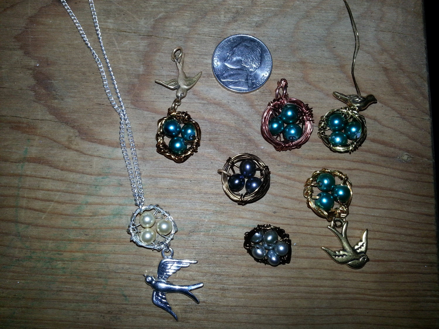 Wire wrapped bird nest pendants with colored beads as the eggs. Bird charms are attached to the nest. Various colors and sizes available.