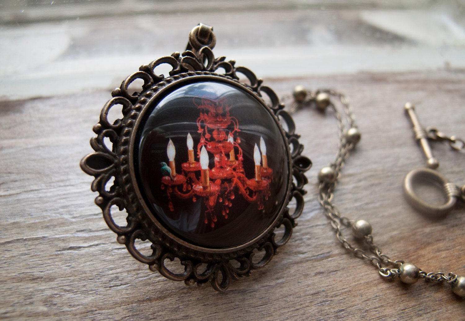 Crimson Perch--A necklace and pendant with an original Illustration of a teal bird perched upon a red crystal chandelier