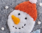 Handmade Christmas ornament, flannel snowman, wool and felt, embroidered, wearing blue scarf and orange hat, holding a tiny ornament