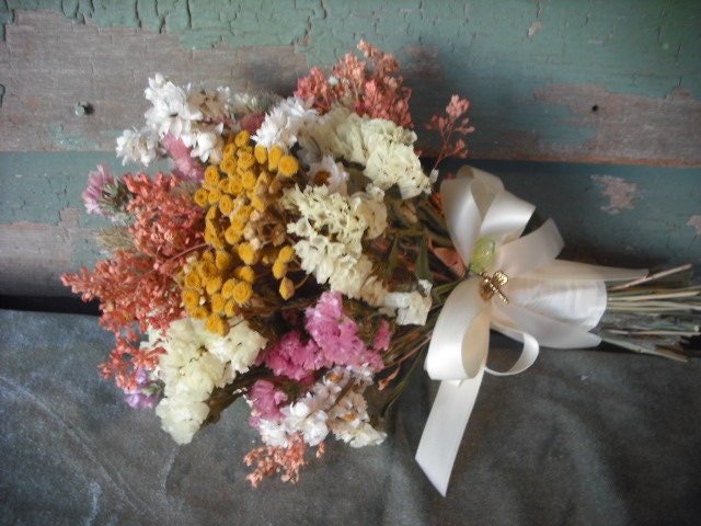 Simple dried flower bridal bouquet in peach, cream and yellows with ivory ribbons and dragonfly charm.