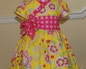 Sweet sunshine wraparound dress in yellow and pink print with ruffled neckline and wide sash