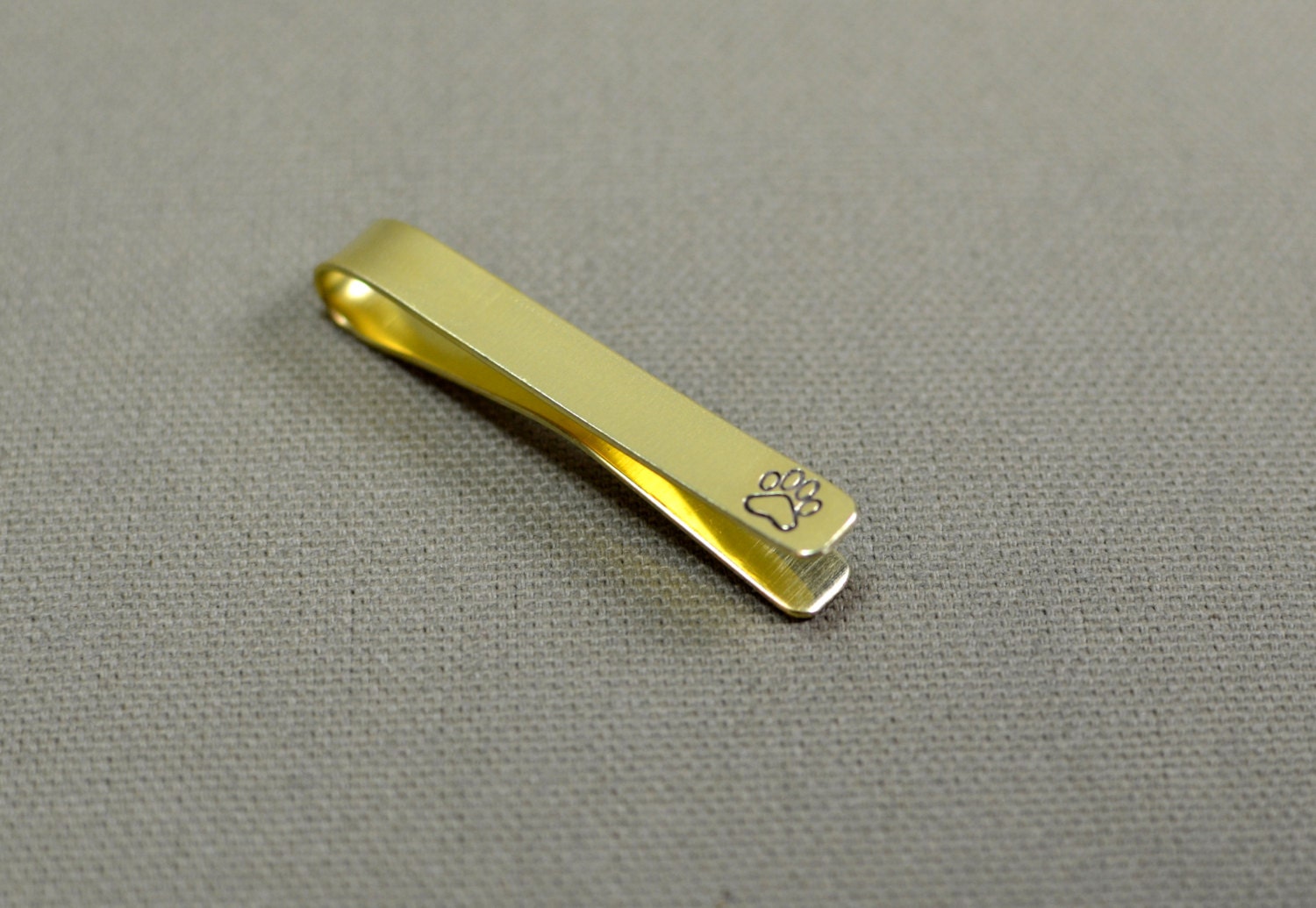 Wild tie bar with a paw print in brass