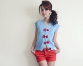 Blue sleeveless cardigan with poppy red leather bows . Monaco
