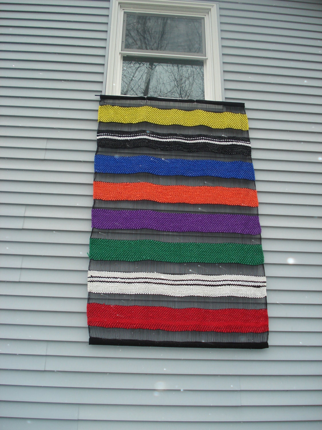 Handwoven wall hanging in stripes of primary colors with open weave