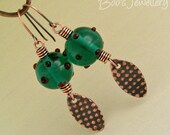 Antiqued copper earrings featuring green hand made glass beads and oval spotty charms