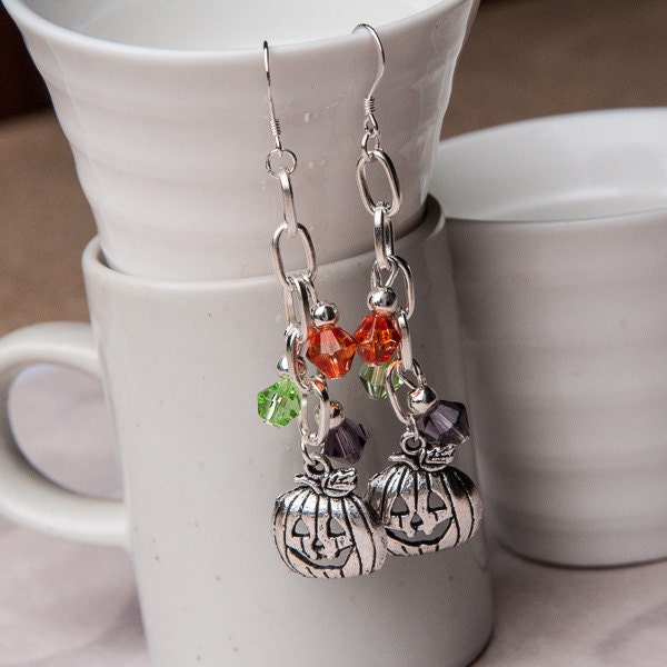 Dangling silver pumpkin earrings with orange and green glass bead