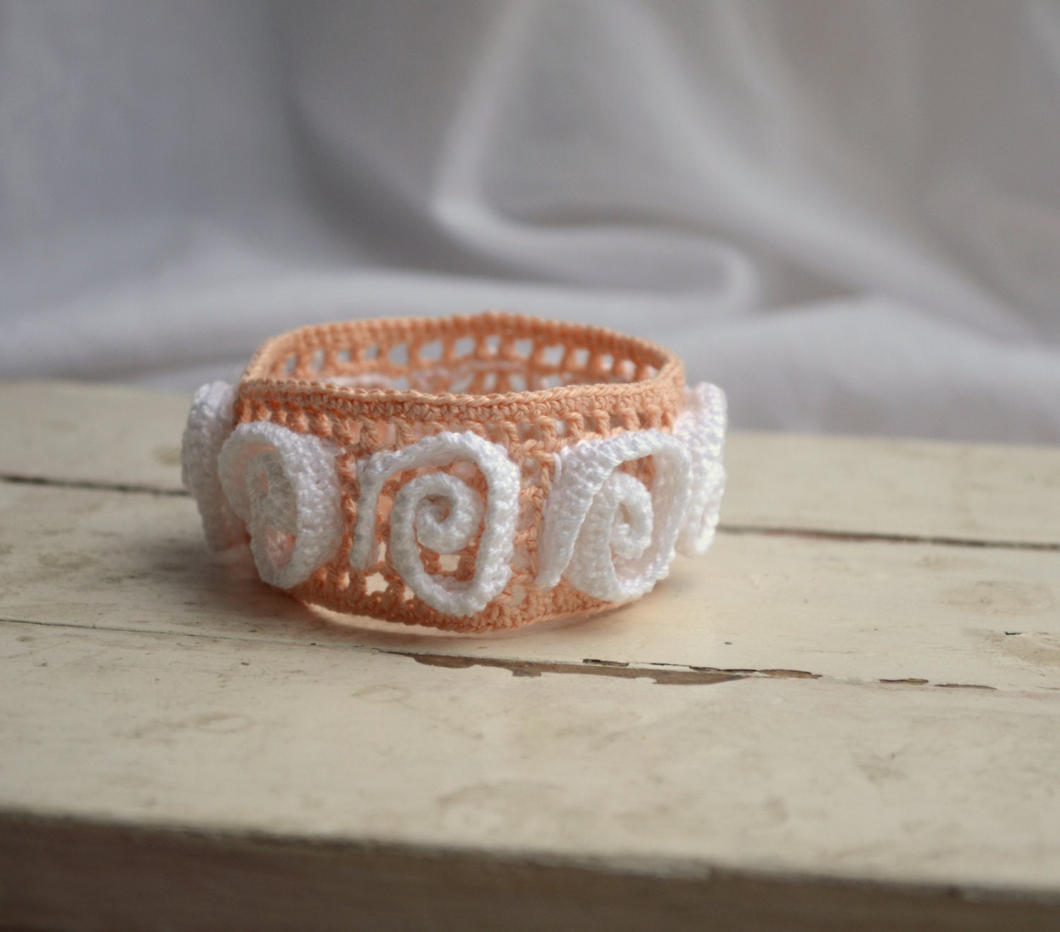 Crocheted peach pink bracelet with white adornment