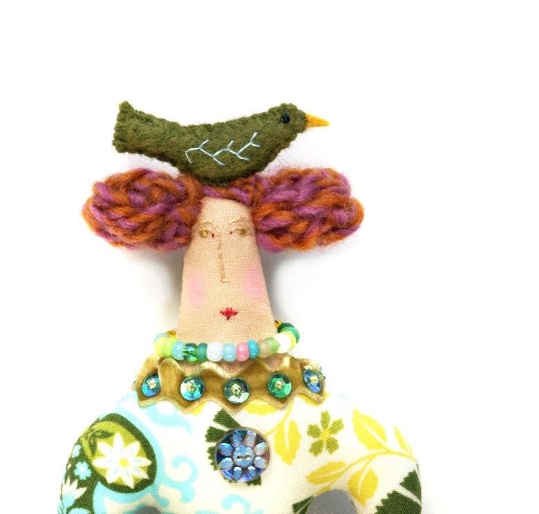 Textile art cloth art doll with green bird on top of her head