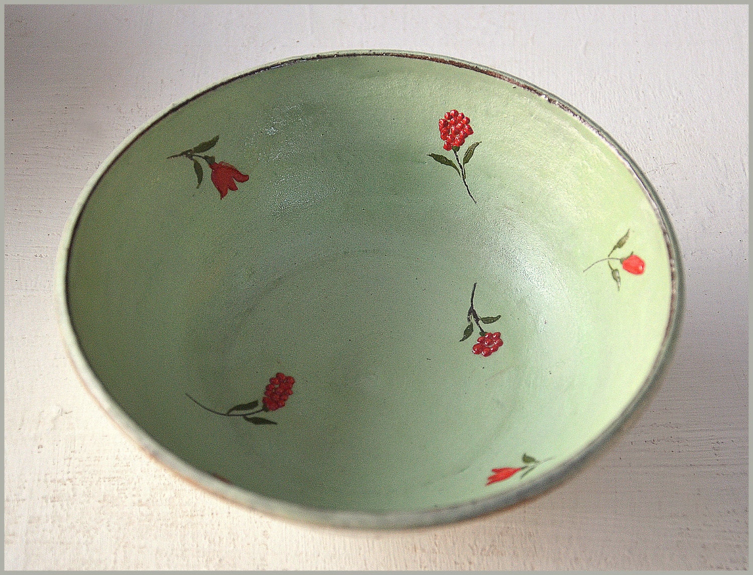 A light- green bowl with red flowers