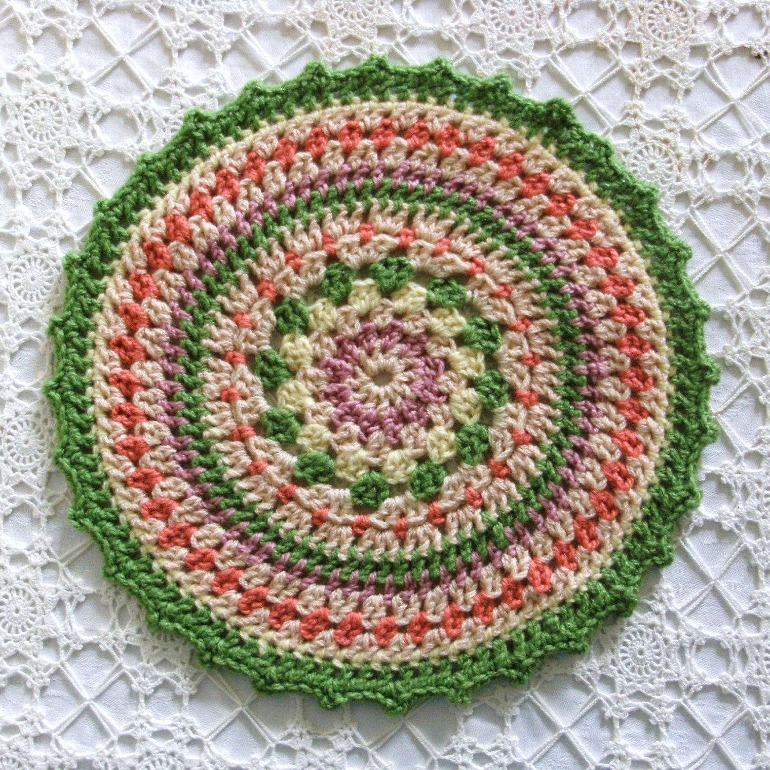Mandala crochet decorative table mat doiley.  Grass green, deep peach, dusky pink and pale pale yellow with lots of linen.