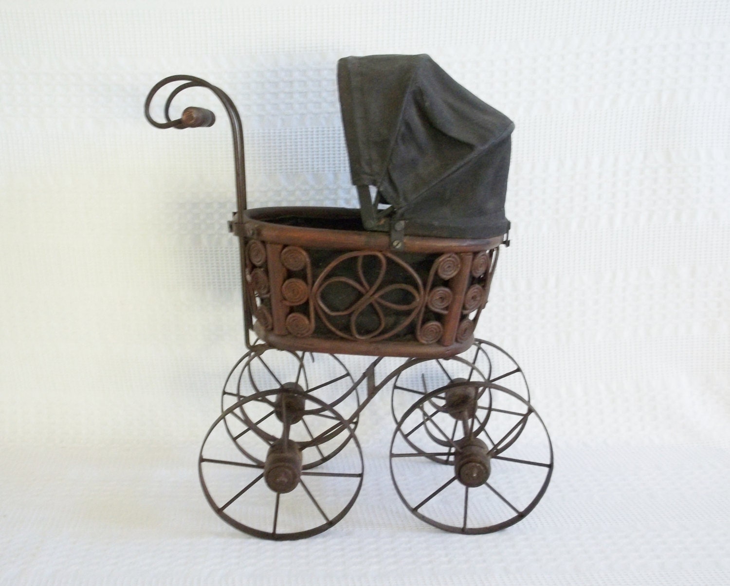 Antique wicker and metal doll pram, carriage, buggy stroller with treated black canvas canopy.