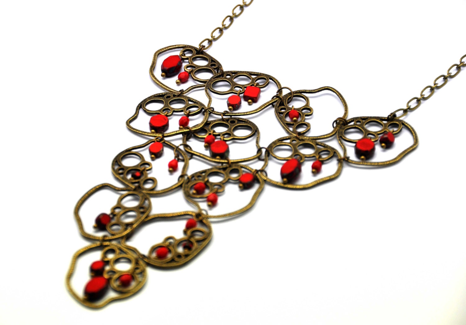 A beautiful necklace made with red  czech glass beads, czech crystals and bubble filigree antiqued brass shapes