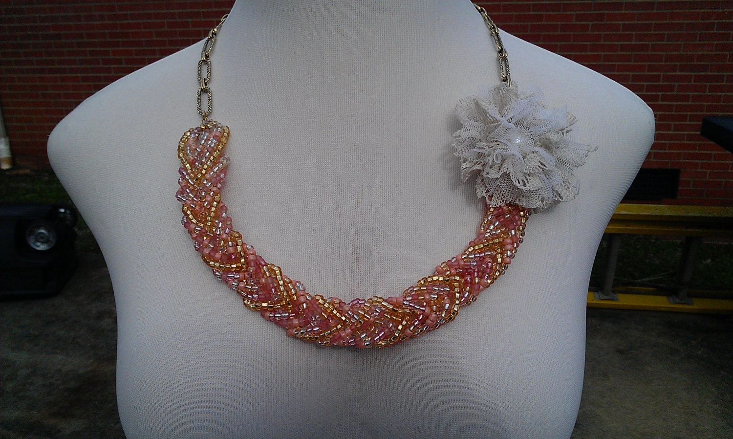 Peach and gold beaded fishtail beaded necklace with lace flower accessory .