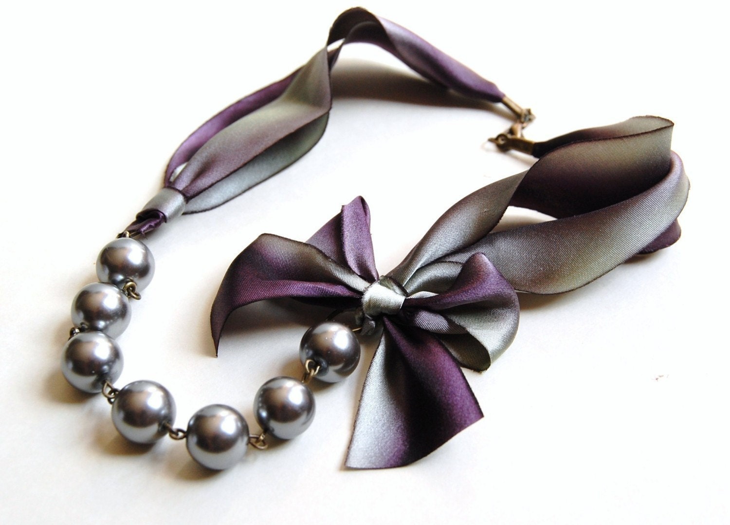 The Carrie Necklace in Stormy A silver and purple romantic ribbon and pearl necklace
