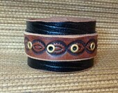 Black leather  tooled double strap cuff with eyelets.