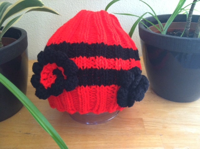 Red and black knitted beanie hat with detachable flowers